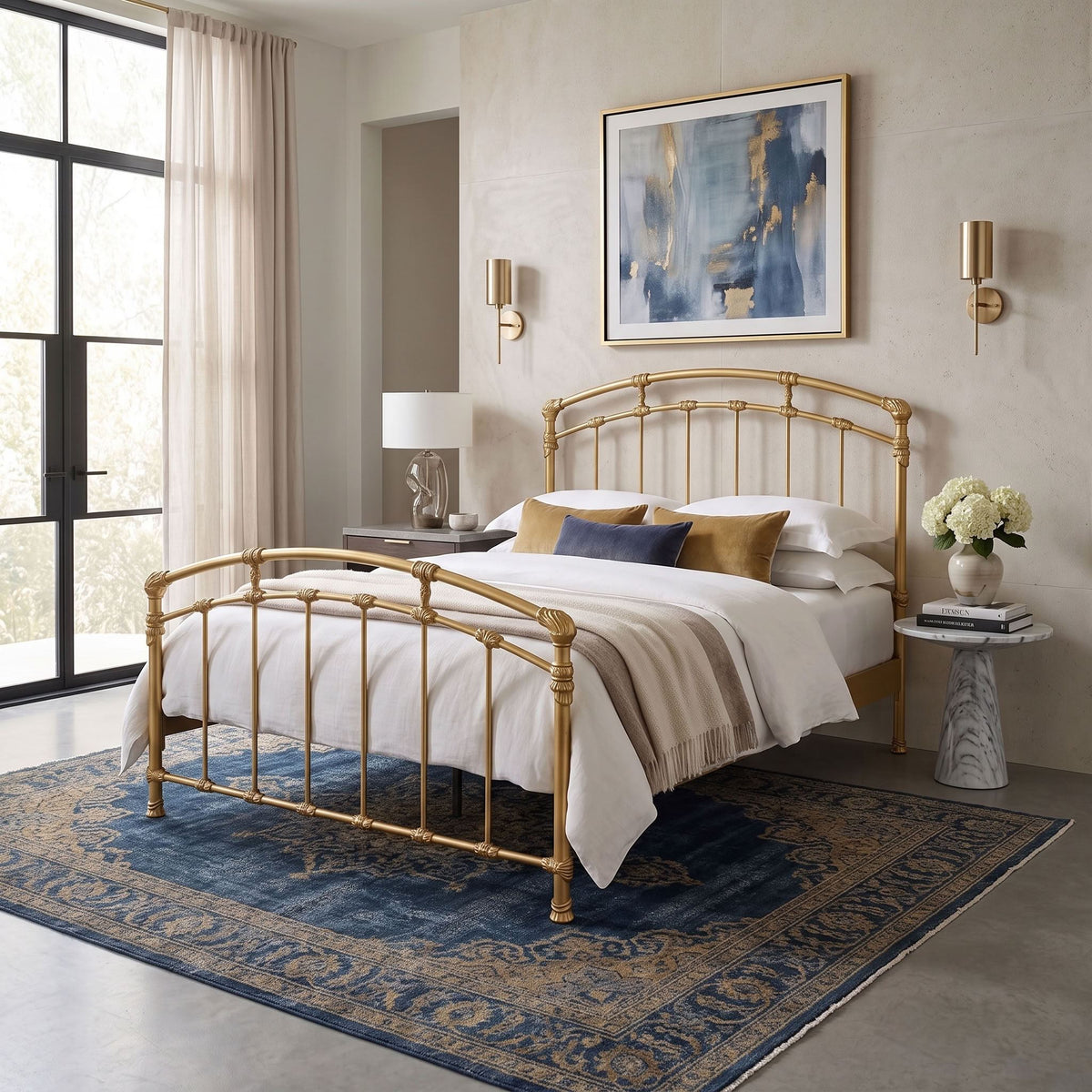 Test Iron Bed by Wesley Allen in Hand Brushed Gold finish in Queen size platform frame with wood slats. A gold metal bed frame with a curved headboard and matching footboard, styled in a modern bedroom setting with white bedding, a blue patterned rug, and neutral-toned walls.
