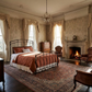 Aristella Iron Bed by Matriae in a luxurious historic bedroom with ornate drapery, fireplace, and elegant decor.